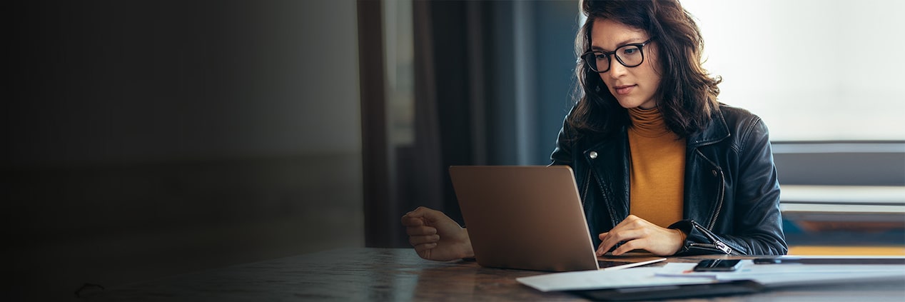 A woman sitting at a desk on her laptop.