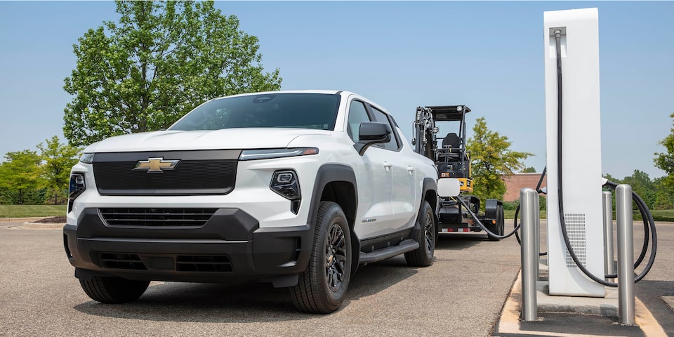 A 2026 Chevy Silverado pulling a trailer while parked at a charging station