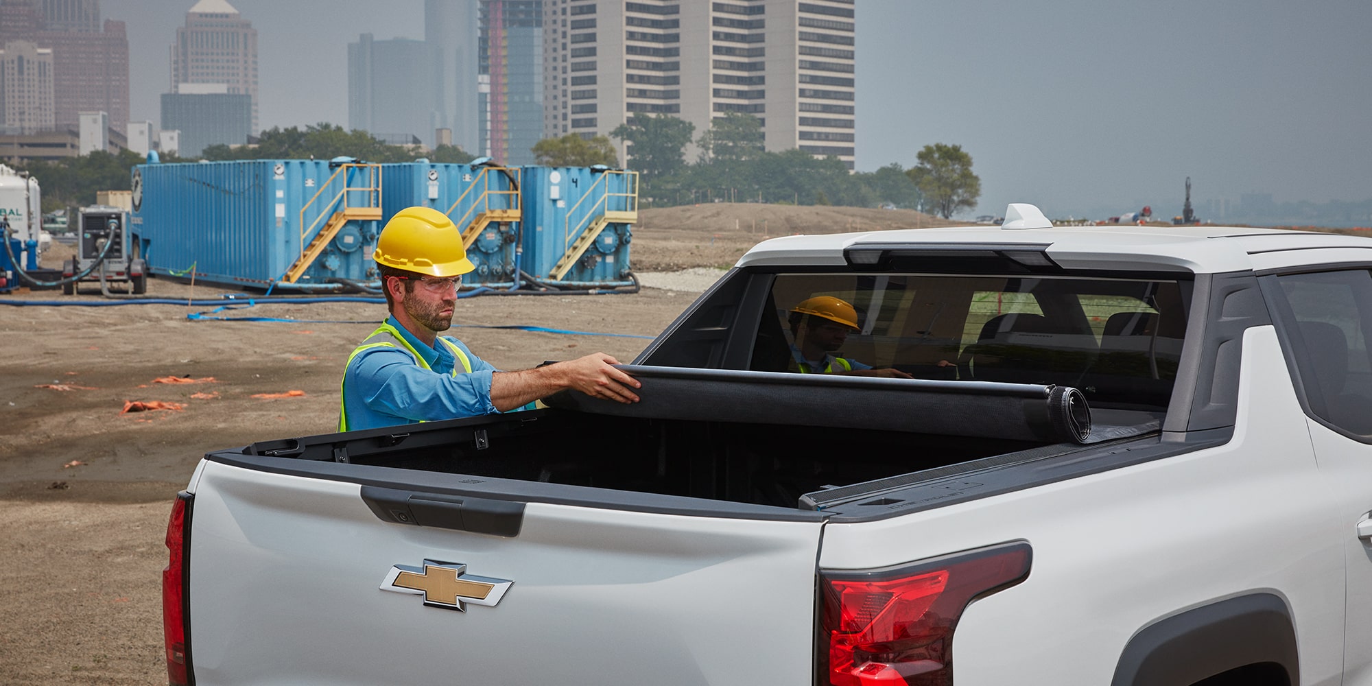 A worker unrolling a truck bed topper on a 2026 Chevy Silverado EV