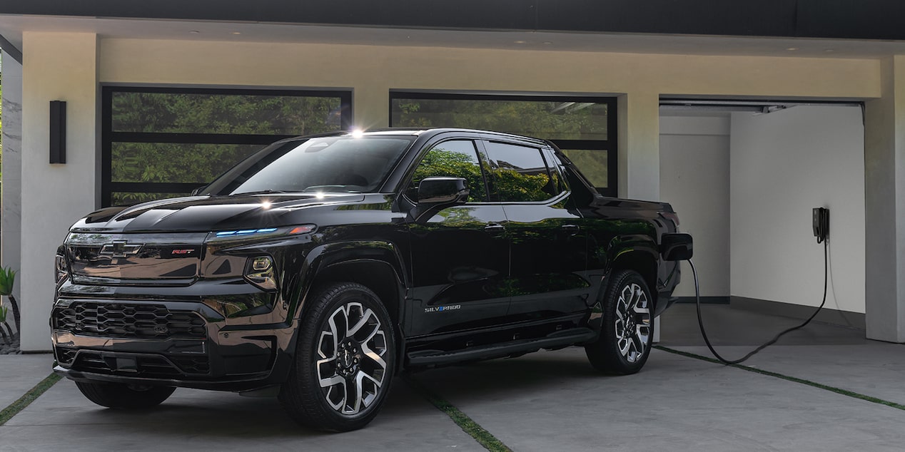 A 2026 Chevy Silverado EV charging in front of a home garage