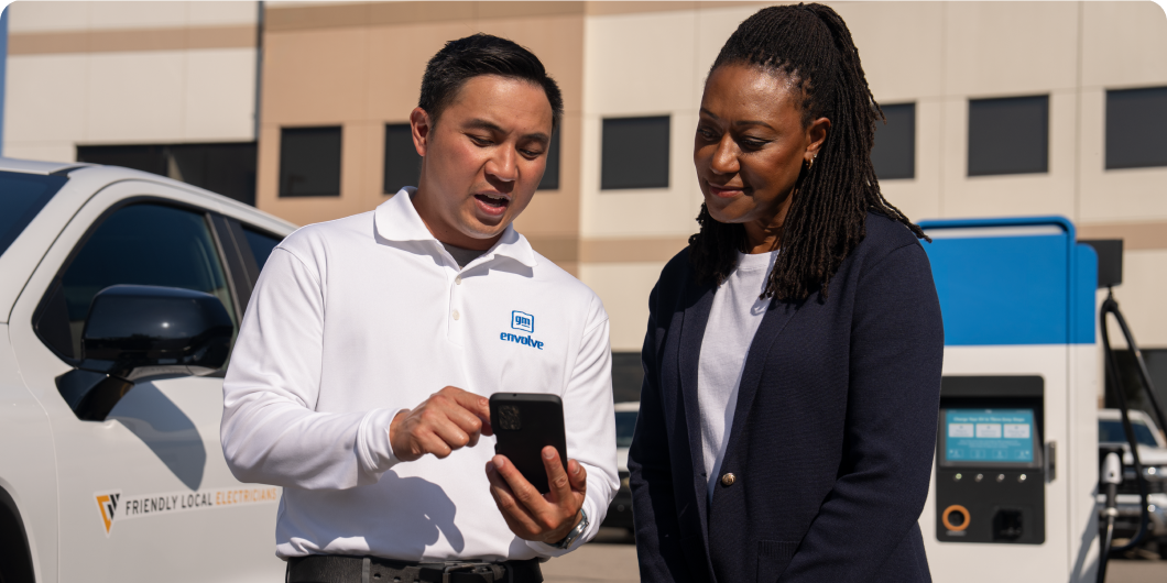 A GM EV Expert talking with a customer at an EV charging station.