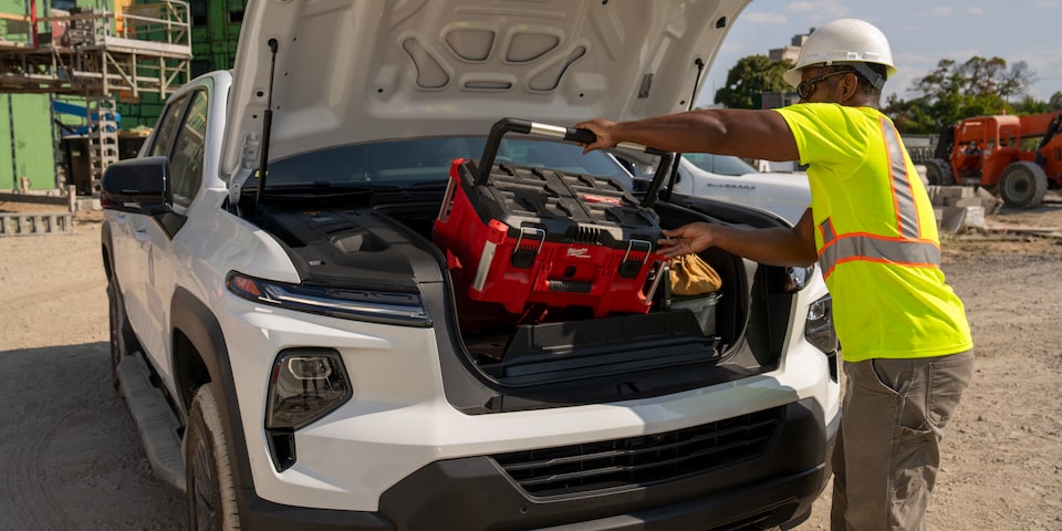A construction worker unloads equipment from the front storage compartment of the Chevrolet Silverado EV.