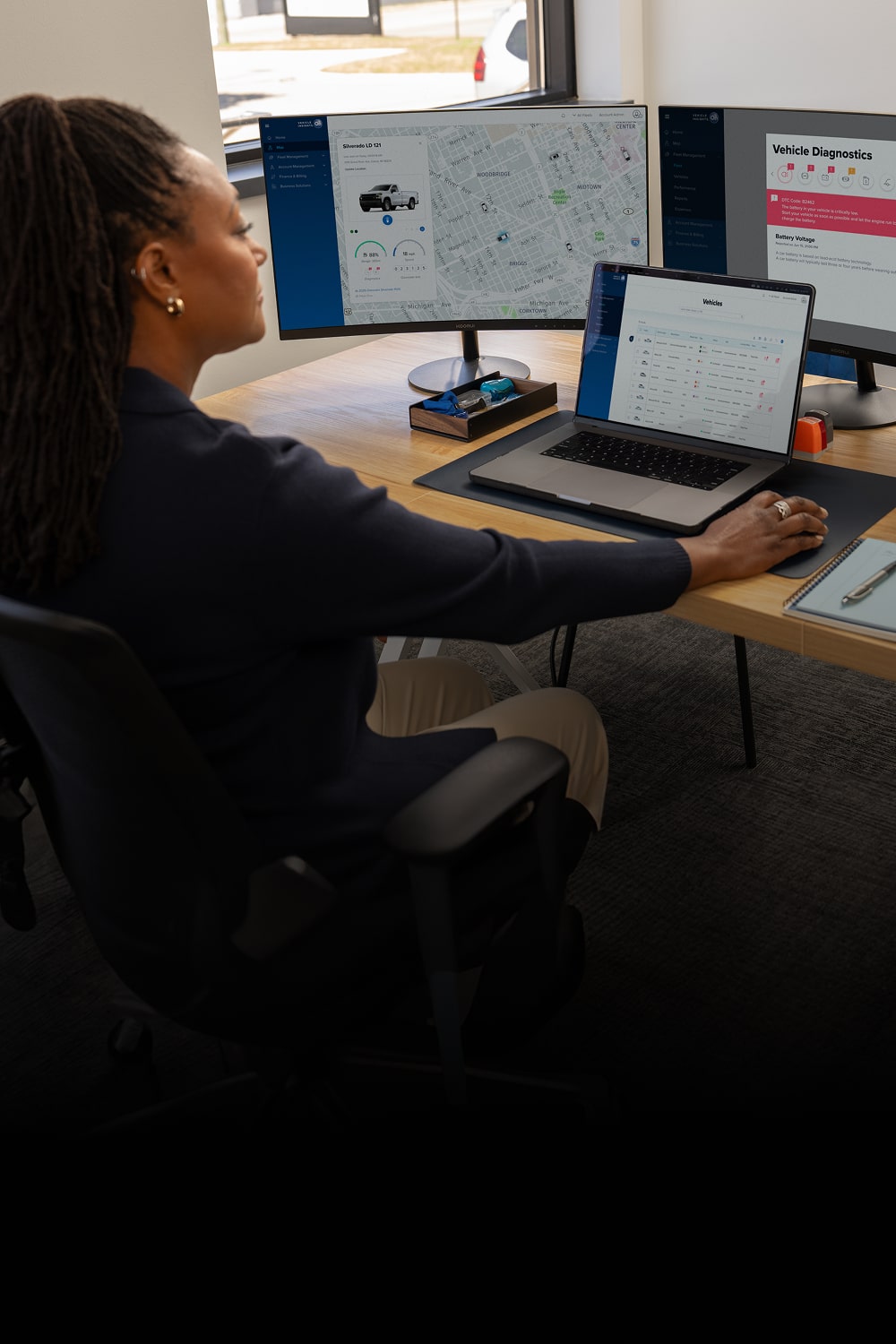 Fleet telematics open on two monitors and a laptop screen.