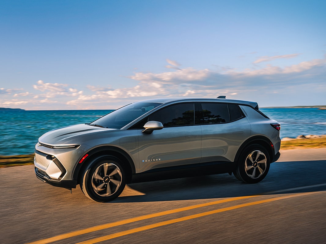 A 2026 Chevrolet Equinox EV driving down an oceanside road
