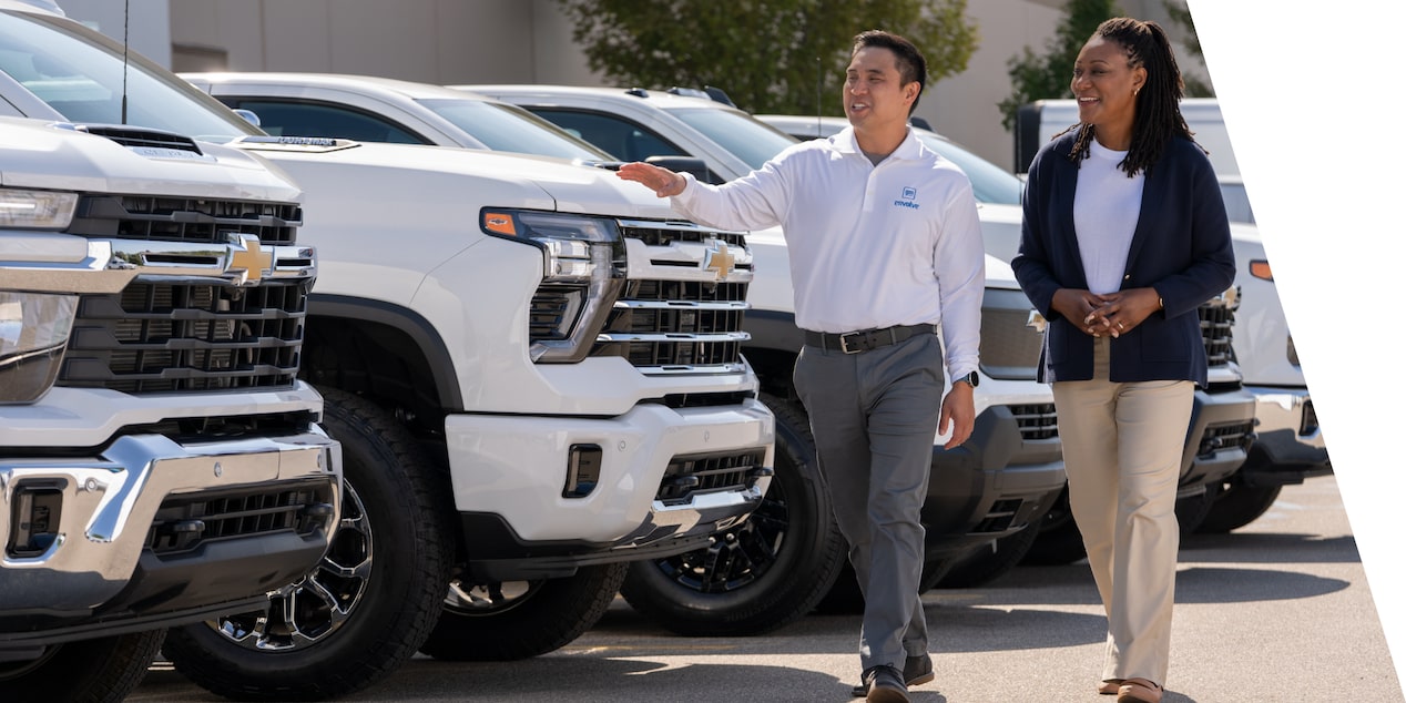 A GM Envolve sales associate showing a lineup of Chevrolet Silverados to a customer