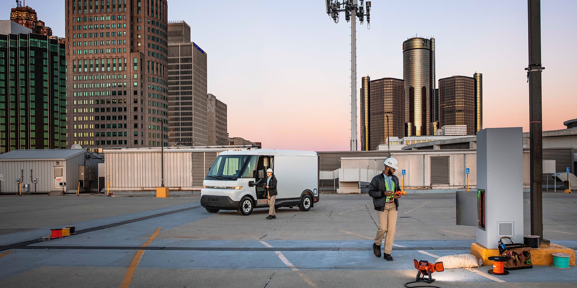 A Chevrolet BrightDrop on a job site. Two workers work nearby.