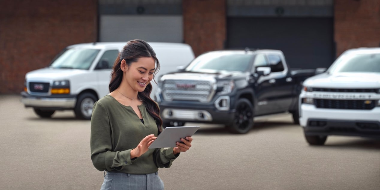 Two people talking in front of three GM Trucks