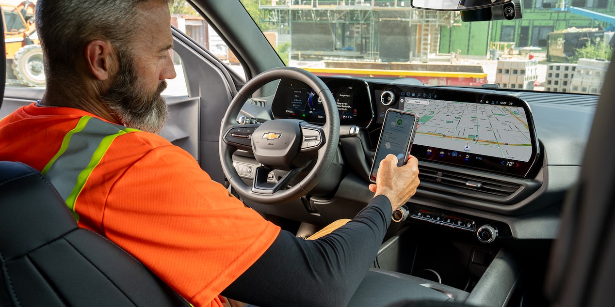 A construction worker checks their phone while sitting in their Chevrolet SIlverado.