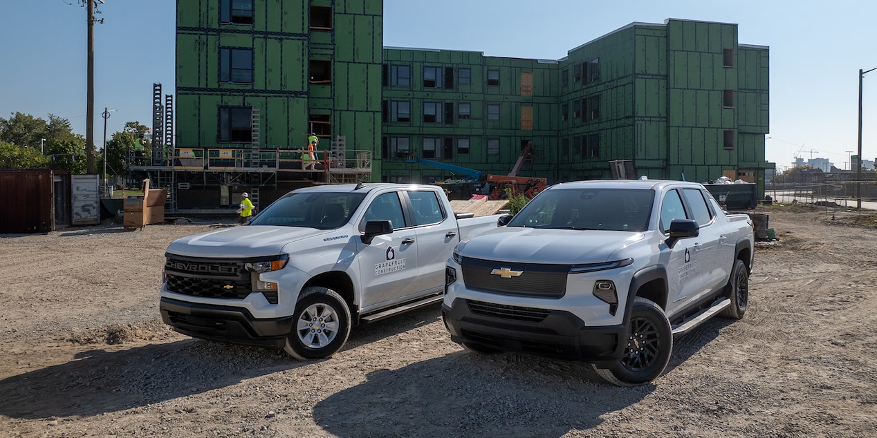 Two White Chevrolet Silverados parked on a construction site.