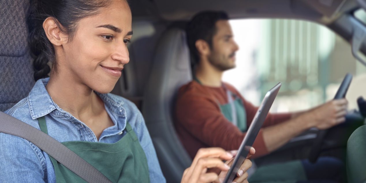 A woman in the passenger seat accessing OnStar Vehicle Insights from a tablet while someone else drives.