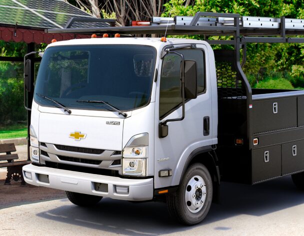 Close-up Three-Quarters Front View of the 2023 Chevrolet Low Cab Forward Truck Parked by a Bus Stop