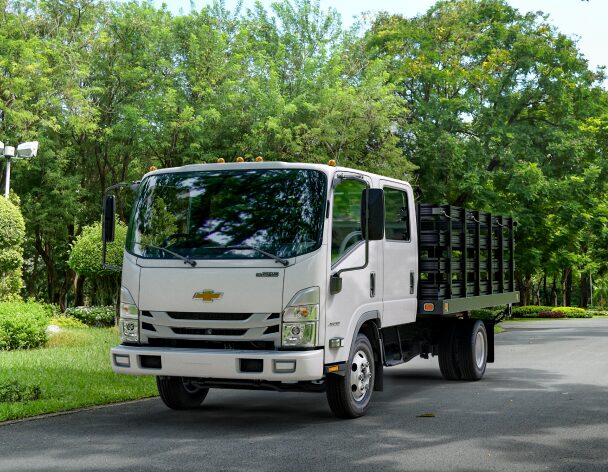 Three-Quarters Front View of the 2023 Chevrolet Low Cab Forward Truck Parked by a Row of Trees
