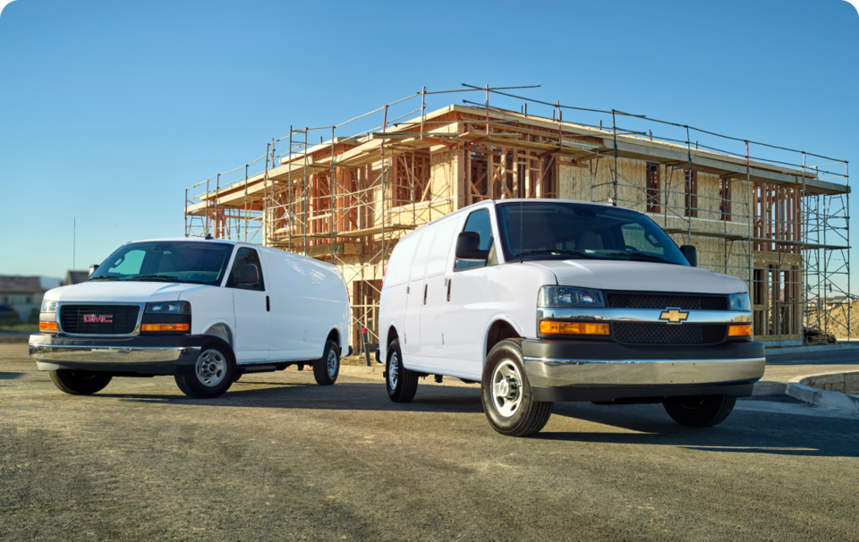 Chevrolet and GMC Passenger Vans Parked Outside at a Job Site