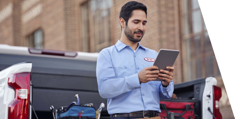 A Man Standing Next to the Trunk of a Truck Using a Tablet